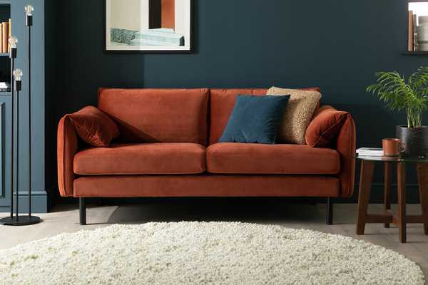 Bexley 3 seater sofa in a rust orange fabric situated against a navy wall.